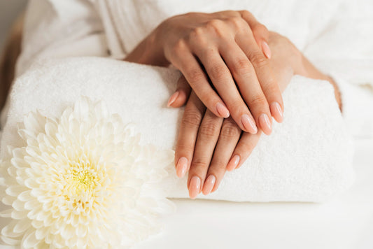Mains d'une femme posées sur un linge à côté d'une fleur pour une manucure