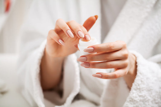 Femme en peignoir avec une manucure avec un pot de crème hydratante dans les mains